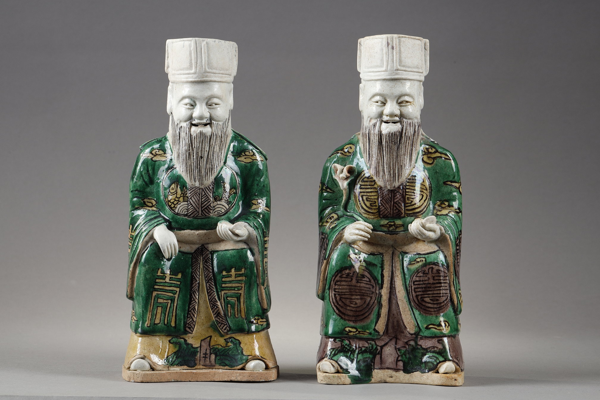 Two "famille verte" biscuit figures representing Chinese dignitaries sitting in majesty holding silver ingots and one with a lotus-branch
China Kangxi period 1662/1722   RESERVED